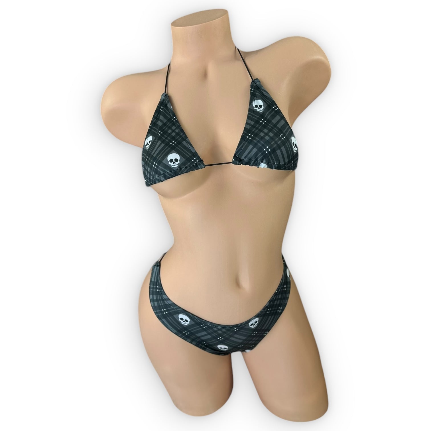 A gray tartan bikini set with black skull triangle top and elastic straps, displayed on a mannequin.  — Golddiggers Boutique exotic dancewear