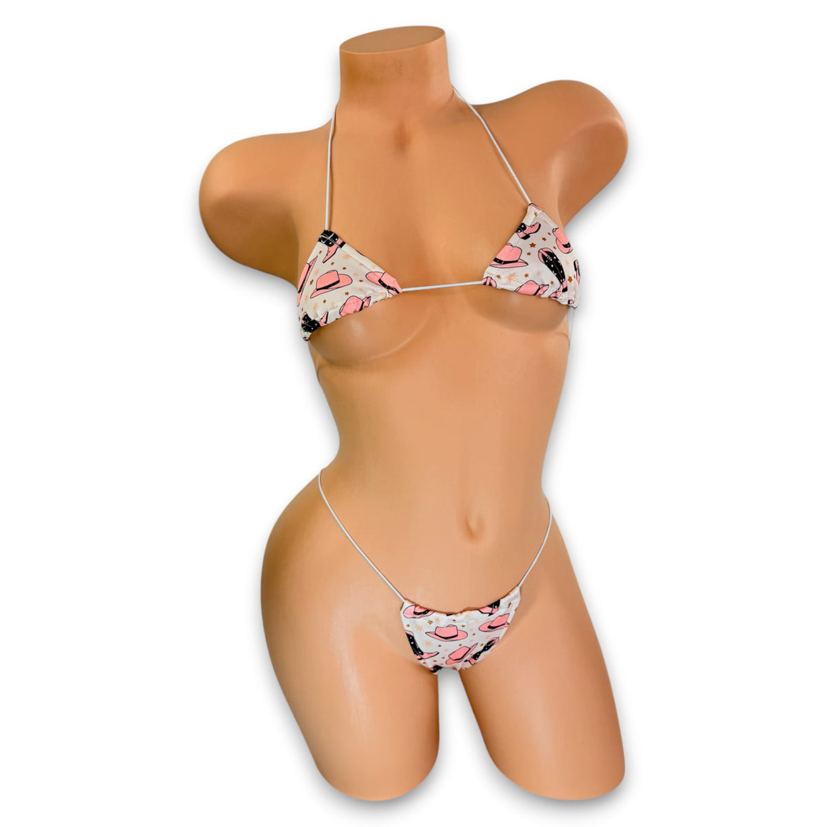 Cream cowgirl print micro 'kini with pink hats and pink and brown boots on mannequin, front view - Golddiggers Boutique