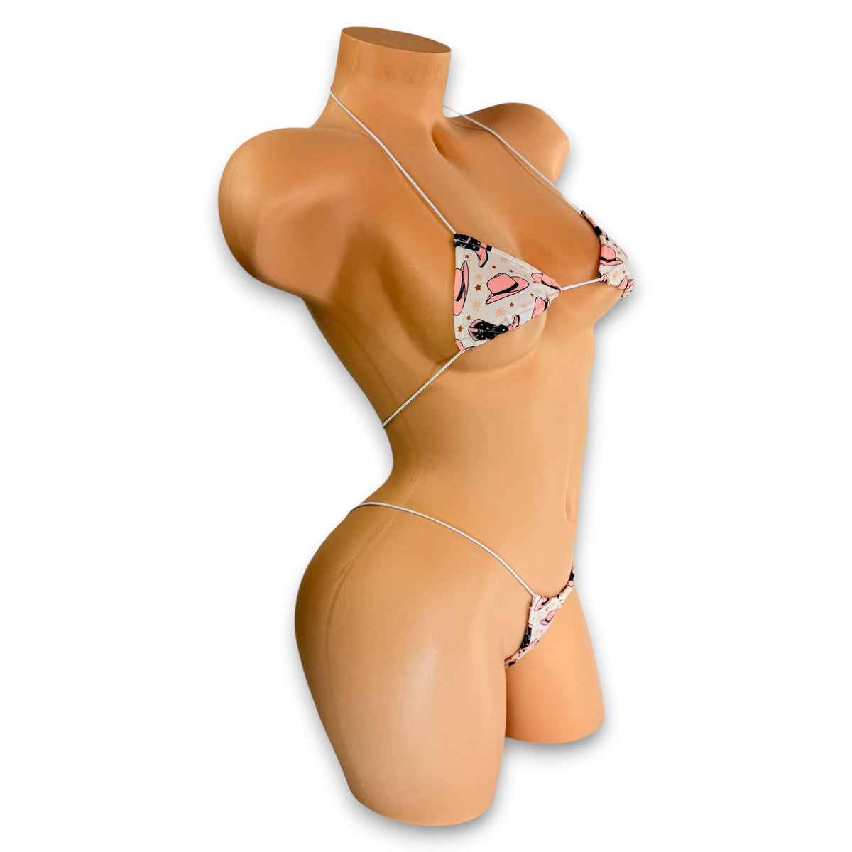 Cream cowgirl print micro 'kini with pink hats and pink and brown boots on mannequin, angled side view - Golddiggers Boutique