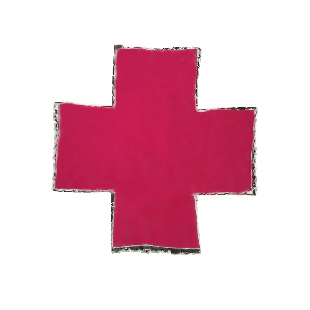Back of a rhinestone cross pasty showing the pink self-adhesive silicone backing