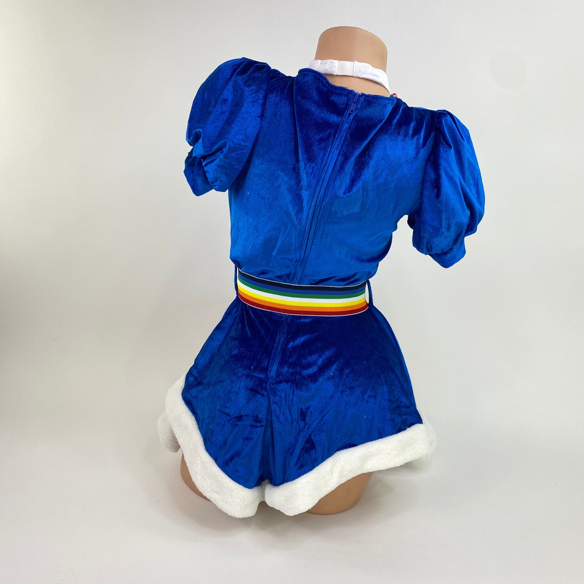 Back view of the royal blue velvet rainbow girl costume showing the zipper, rainbow belt, and white fur hem