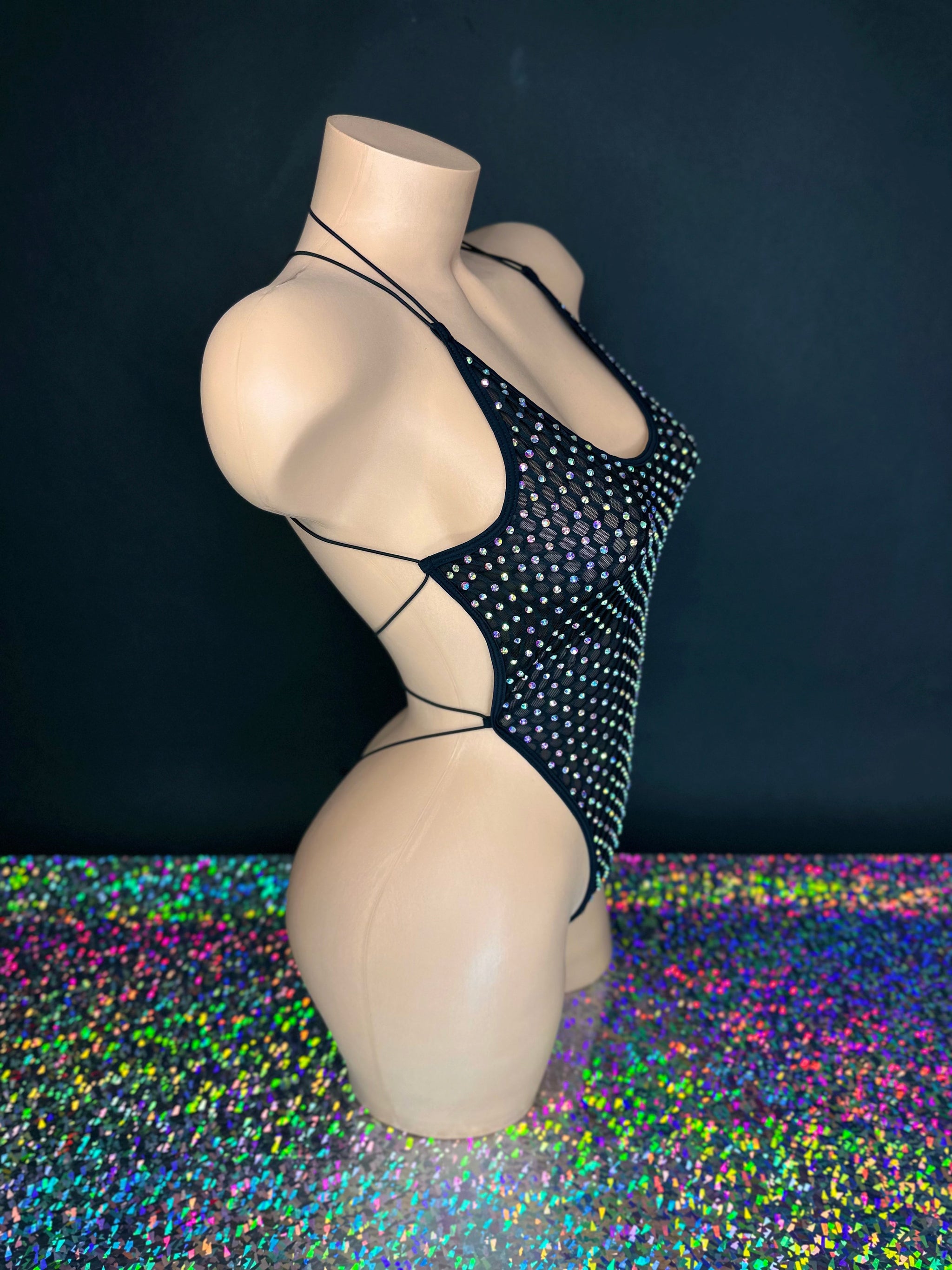 Veronica black rhinestone bodysuit, side view on dark background with holographic floor - Golddiggers Boutique